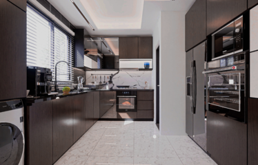 A 2 bedroom townhouse for sale in Adenta Accra showing the kitchen with light grey tiled floor and wooded shaded cabinets.