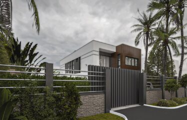 A view from the front gate of a townhouse a 3 bedroom storey house. The walls are short with metal balusters that allow you to see the upper portion of the house.