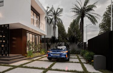 The entrace view of a 3 bedroom house with a blue BMW car parked inside the house - Regimanuel Satellite City Adenta